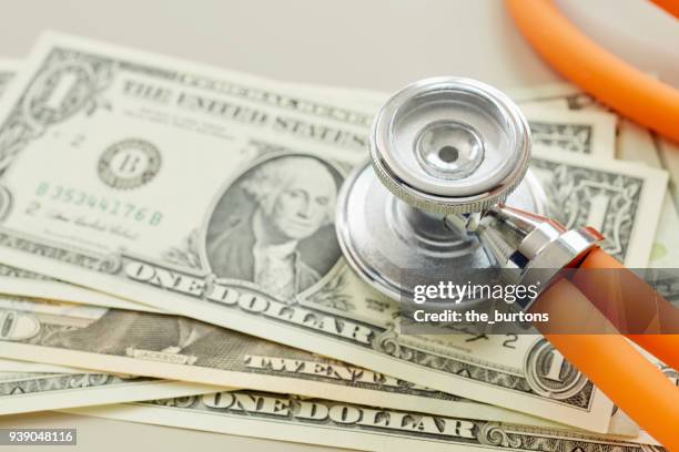 close-up of american dollar banknotes with stethoscope - medicare krankenversicherung stock-fotos und bilder