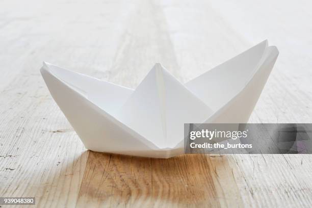 still life of white paper boat on table - folding origami stock pictures, royalty-free photos & images