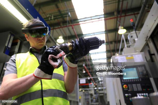 An employee wears a pair of Hololens 3D glasses while holding gear wheels for an automatic automobile transmission system during an Industry 4.0...