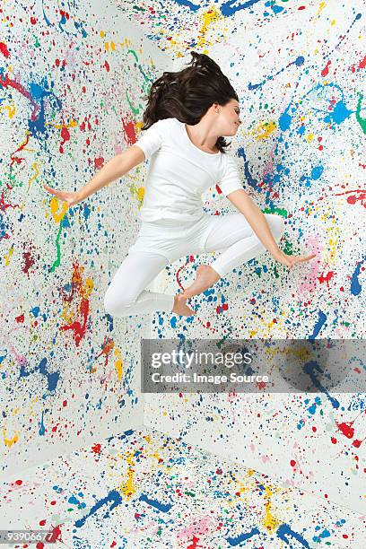 woman jumping and walls covered in paint - paint mid air stock pictures, royalty-free photos & images