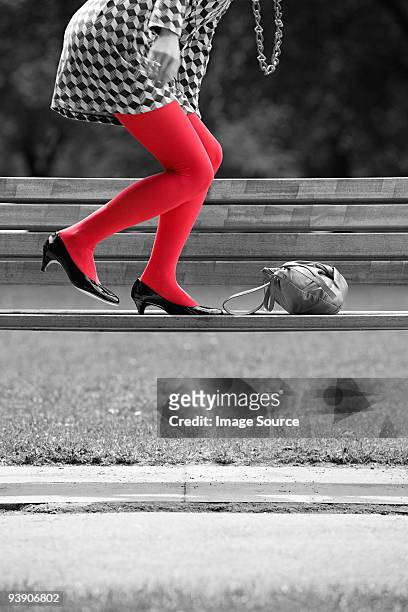femme sur un banc, avec les collants rouge - touche de couleur photos et images de collection