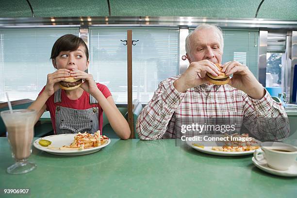 girl and old man eating burgers in a diner - antic cafe stock pictures, royalty-free photos & images