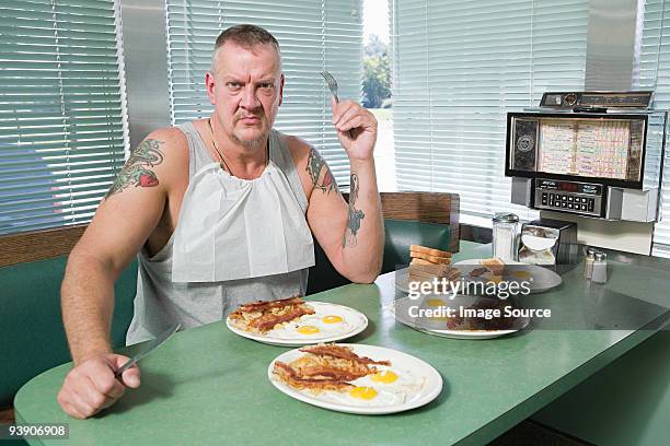 hostile man with plates of fried food - english breakfast stock-fotos und bilder