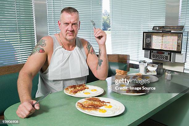 hostile man with plates of fried food - english breakfast stock pictures, royalty-free photos & images