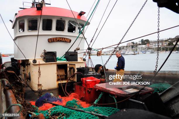 British fisherman Barry Stockton hauls crates of freshly caught fish aboard fishing trawler 'Stephanie' docked in the harbour in the fishing town of...