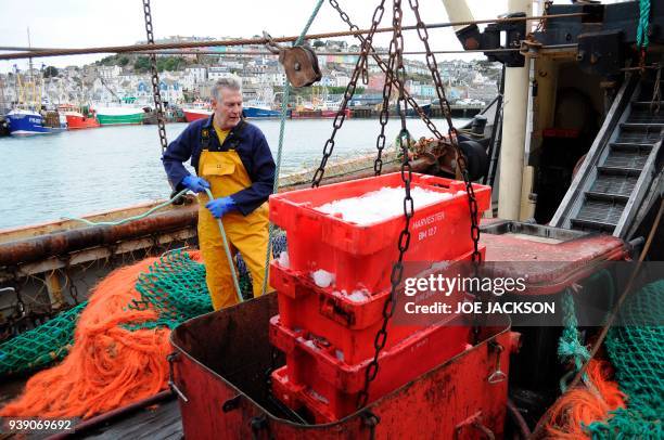 British fisherman Barry Stockton hauls crates of freshly caught fish aboard fishing trawler 'Stephanie' docked in the harbour in the fishing town of...