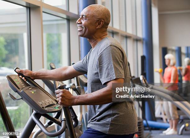 african man working out on elliptical machine - cross trainer stock-fotos und bilder