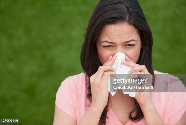 hispanic woman blowing nose - closeup of a hispanic woman sneezing stock pictures, royalty-free photos & images