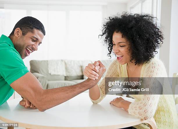 couple arm wrestling at table - arm wrestle stock pictures, royalty-free photos & images