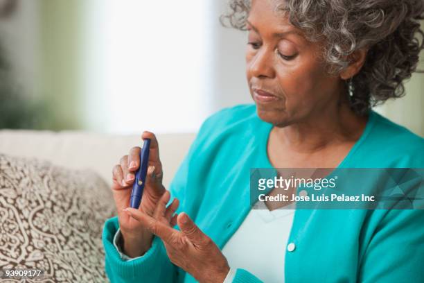 african woman using diabetes test kit - diabetes lifestyle stock pictures, royalty-free photos & images