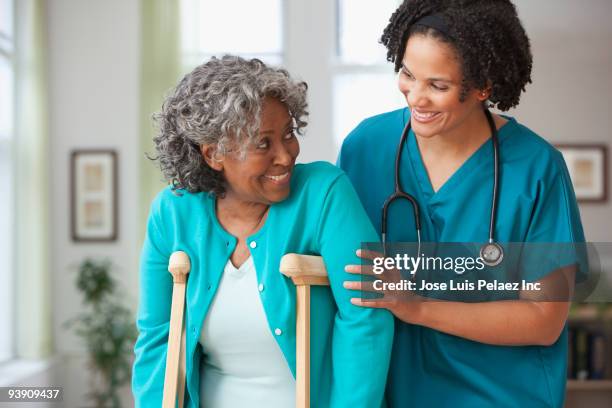 african home nurse helping woman on crutches - patient safety - fotografias e filmes do acervo