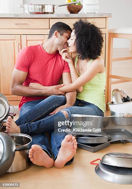 couple kissing on kitchen floor surrounded by pots and pans - messy boyfriend stock pictures, royalty-free photos & images