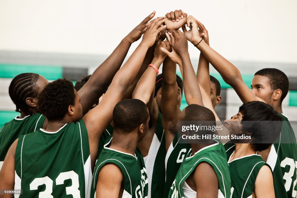 Basketball team with arms raised in huddle
