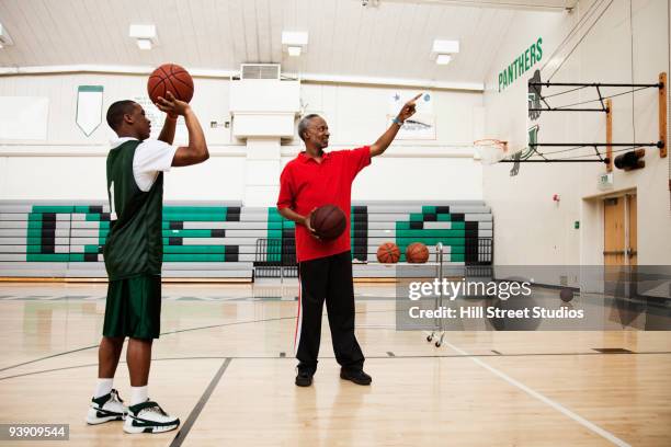 african coach guiding basketball player in gym - tiro libre encestar fotografías e imágenes de stock