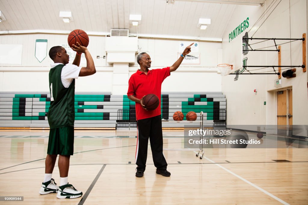 African coach guiding basketball player in gym