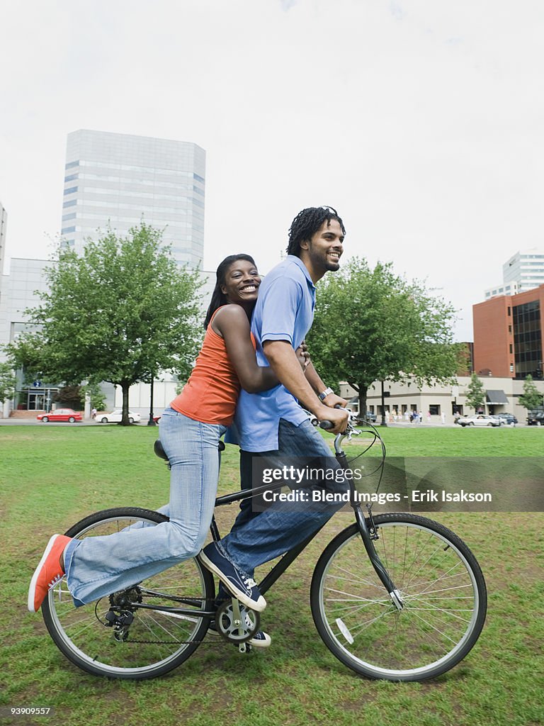 Couple riding bicycle in urban park