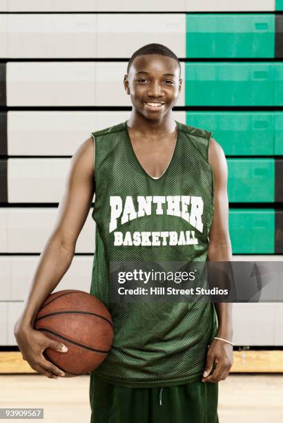 african basketball player holding ball in gym - basketbaltenue stockfoto's en -beelden