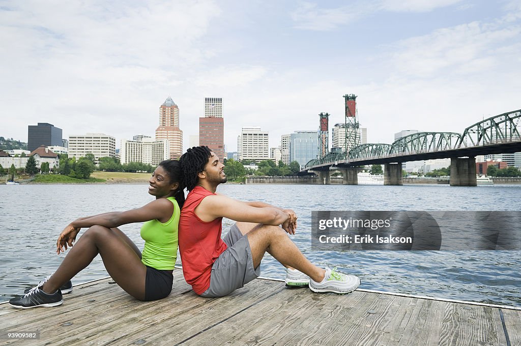 Couple sitting on urban boardwalk along river