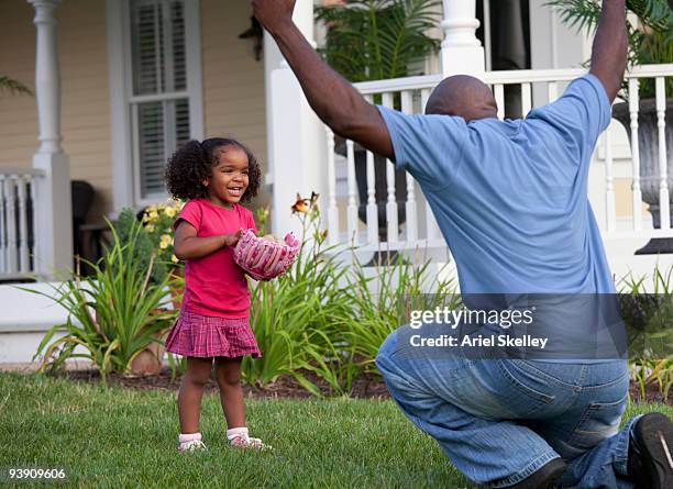 father and daughter playing catch in front yard - father and daughter play imagens e fotografias de stock