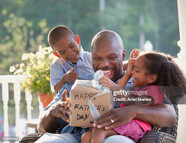 boy and girl watching father open father's day gift - fathers day stock pictures, royalty-free photos & images