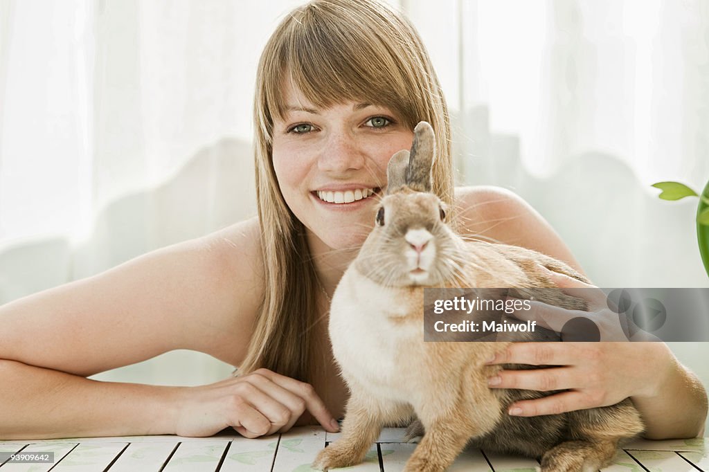 Young woman and a pet rabbit on a patio