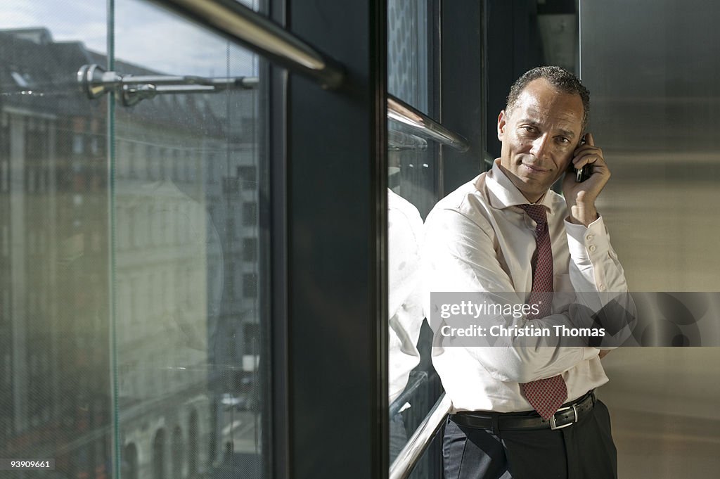 Man leaning at window using cell phone