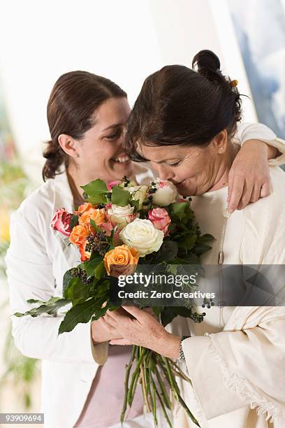 daughter giving her mother flowers - receiving flowers stock pictures, royalty-free photos & images