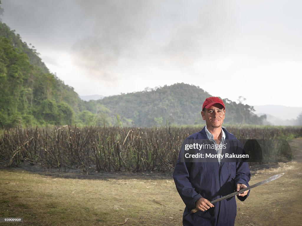 Worker With Machete And Burnt Sugar Cane