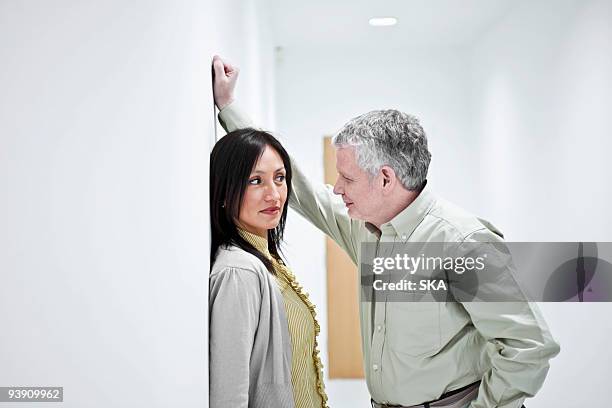 suggestive couple in corridor - harassment work stockfoto's en -beelden