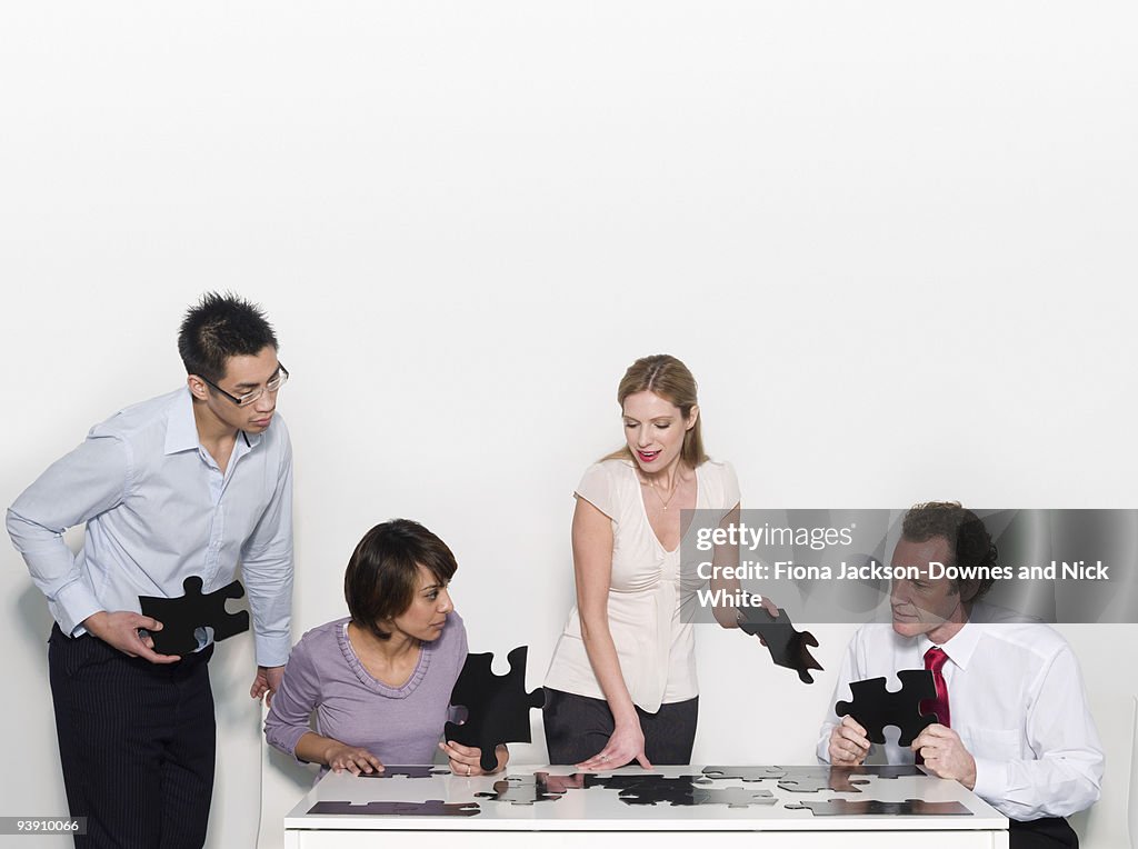 Four business people doing a jigsaw