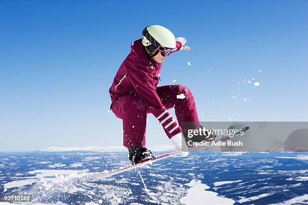 girl in jumpsuit grabbing board mid-air. - sweden snowboarding stock pictures, royalty-free photos & images