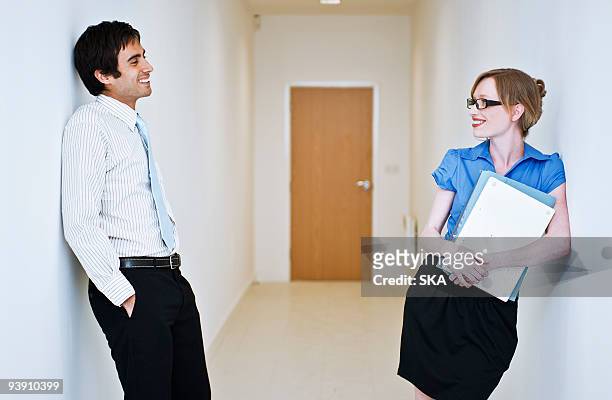 couple chatting in corridor - romance de oficina fotografías e imágenes de stock