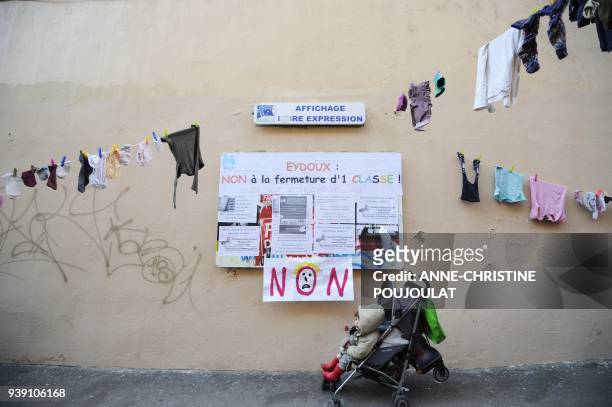 Child sits in a stroller next to children's clothes hung in front of the Eydoux primary school, on February 23 in Marseille, southern France, as...