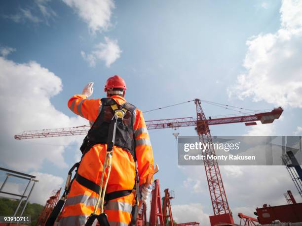 crane worker directing cranes - grue photos et images de collection