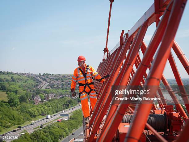 crane worker on arm of crane - crane construction machinery stock-fotos und bilder