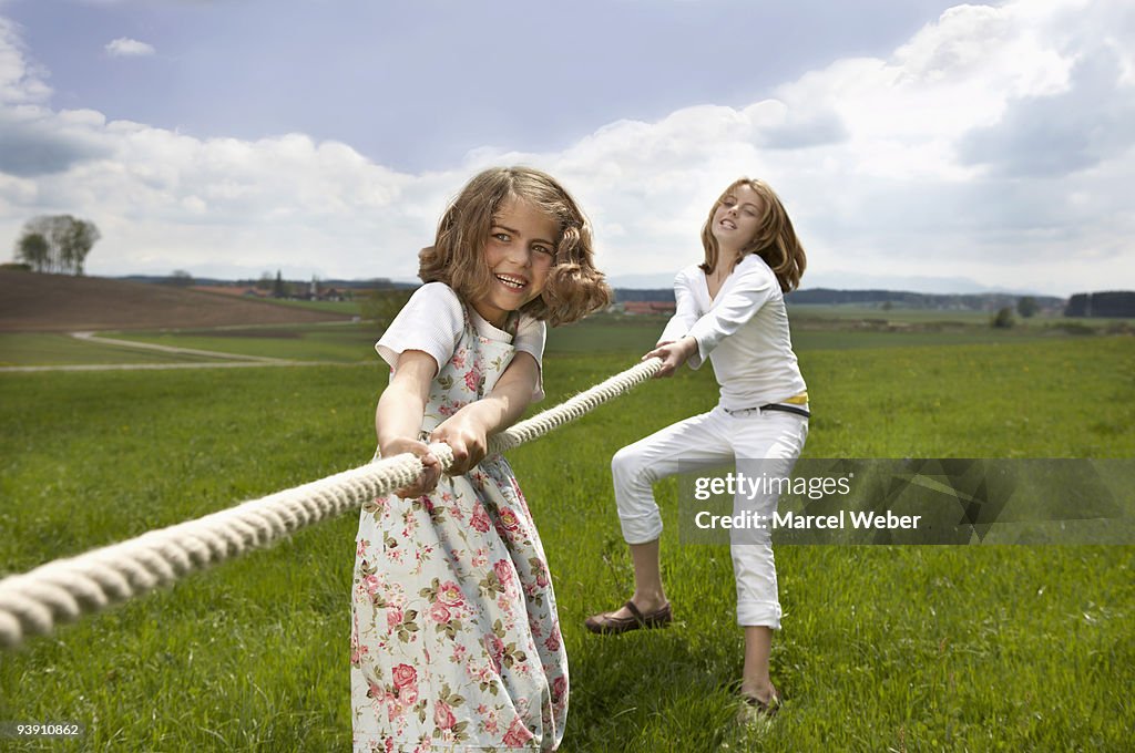 Children pulling a rope in countryside