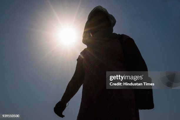 Girl covers her face with a scarf to protect the face from the heat as she walk under the harsh sunlight at Mahalaxmi, on March 26, 2018 in Mumbai,...