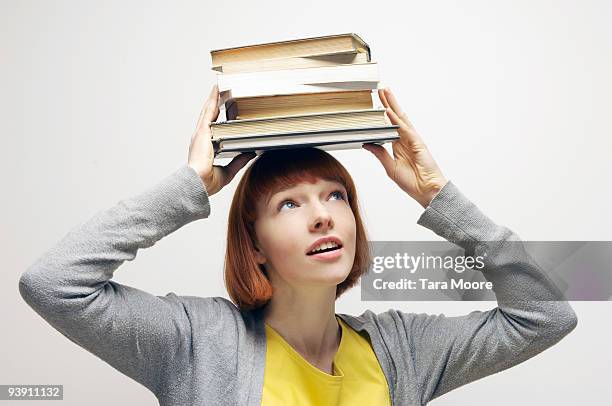 woman balancing books on head - pile of books white background stockfoto's en -beelden