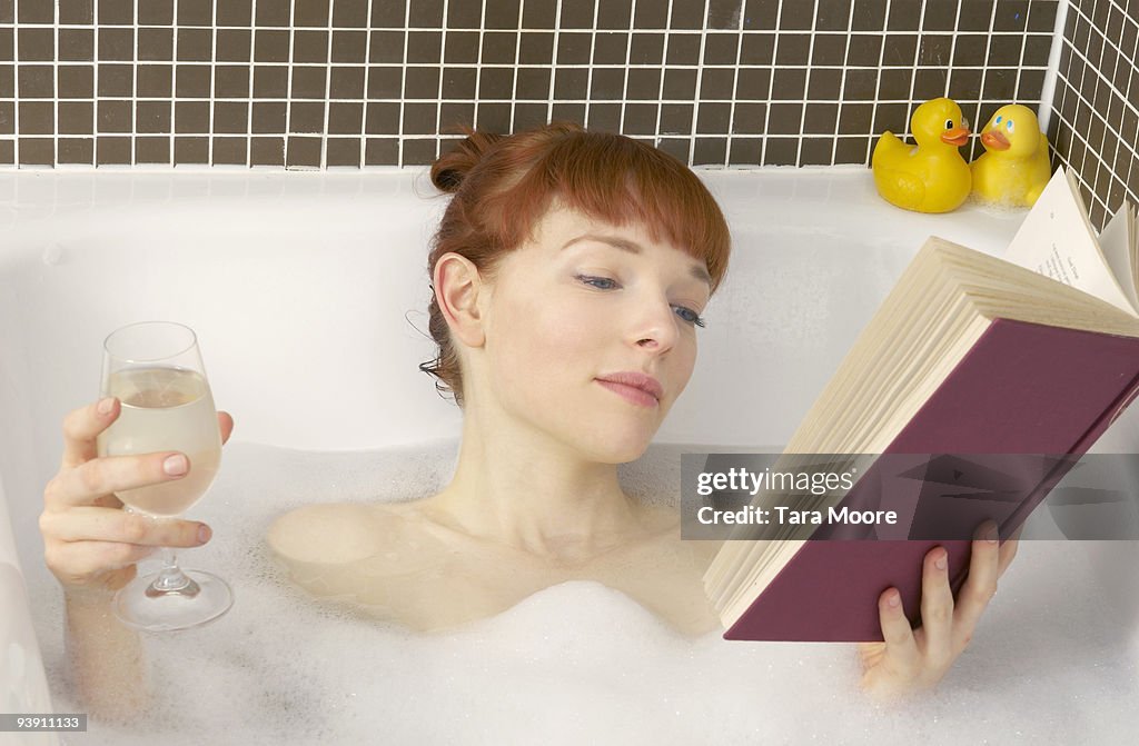 Woman relaxing in bath with book