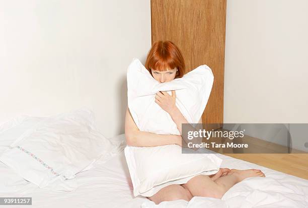 woman on bed hugging pillow - woman pillow stock pictures, royalty-free photos & images