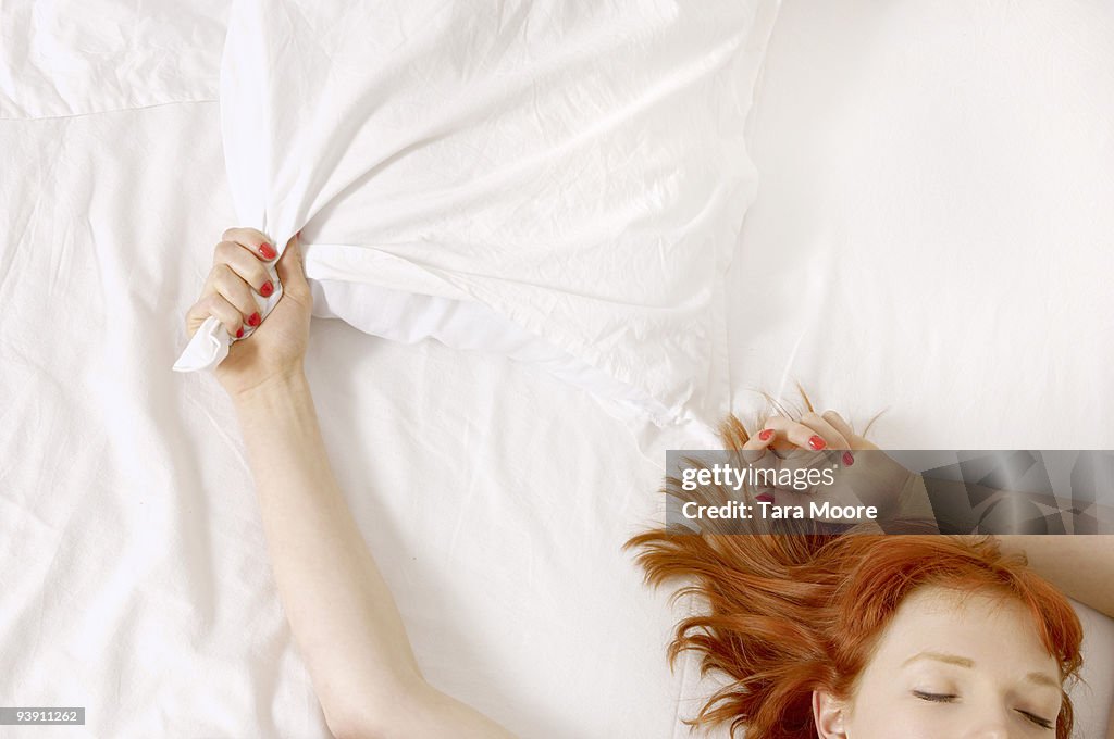 Woman holding on to pillow in bed