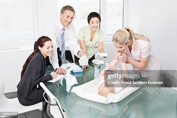 a mother changing a baby in a meeting - london toy fair stock pictures, royalty-free photos & images