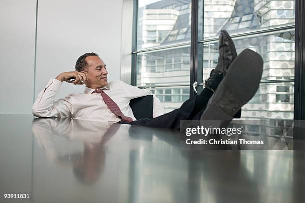 man sitting at table feet up - zurücklehnen stock-fotos und bilder