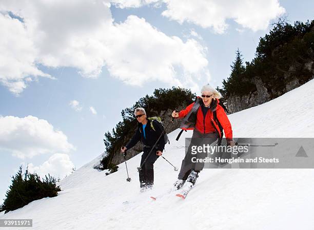 senior couple skiing in mountains - senior winter sport stock pictures, royalty-free photos & images