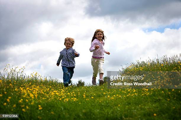 2 young children running. - ross woodhall stock-fotos und bilder