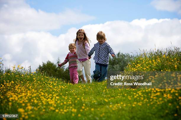 3 young children running. - ross woodhall stock-fotos und bilder