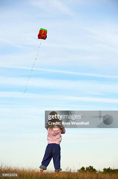 girl flying a kite in a field - ross woodhall stock-fotos und bilder