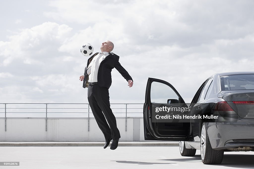 Man playing football near car