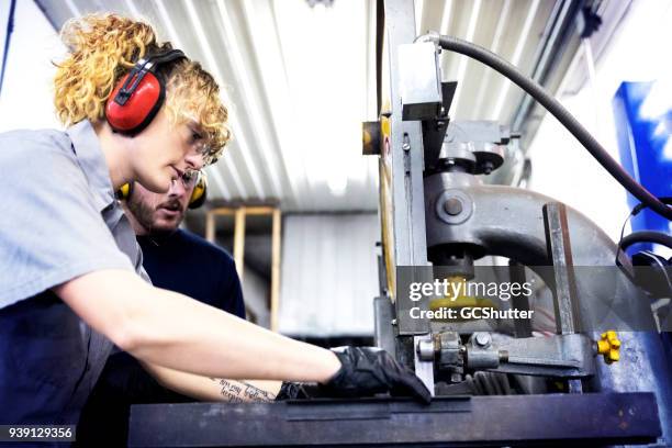 female mechanic using a loud machine in her garage. - boom for real stock pictures, royalty-free photos & images