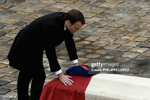 French President Emmanuel Macron places his hands on the flag-draped coffin of Lieutenant-Colonel Arnaud Beltrame after awarding him posthumously...